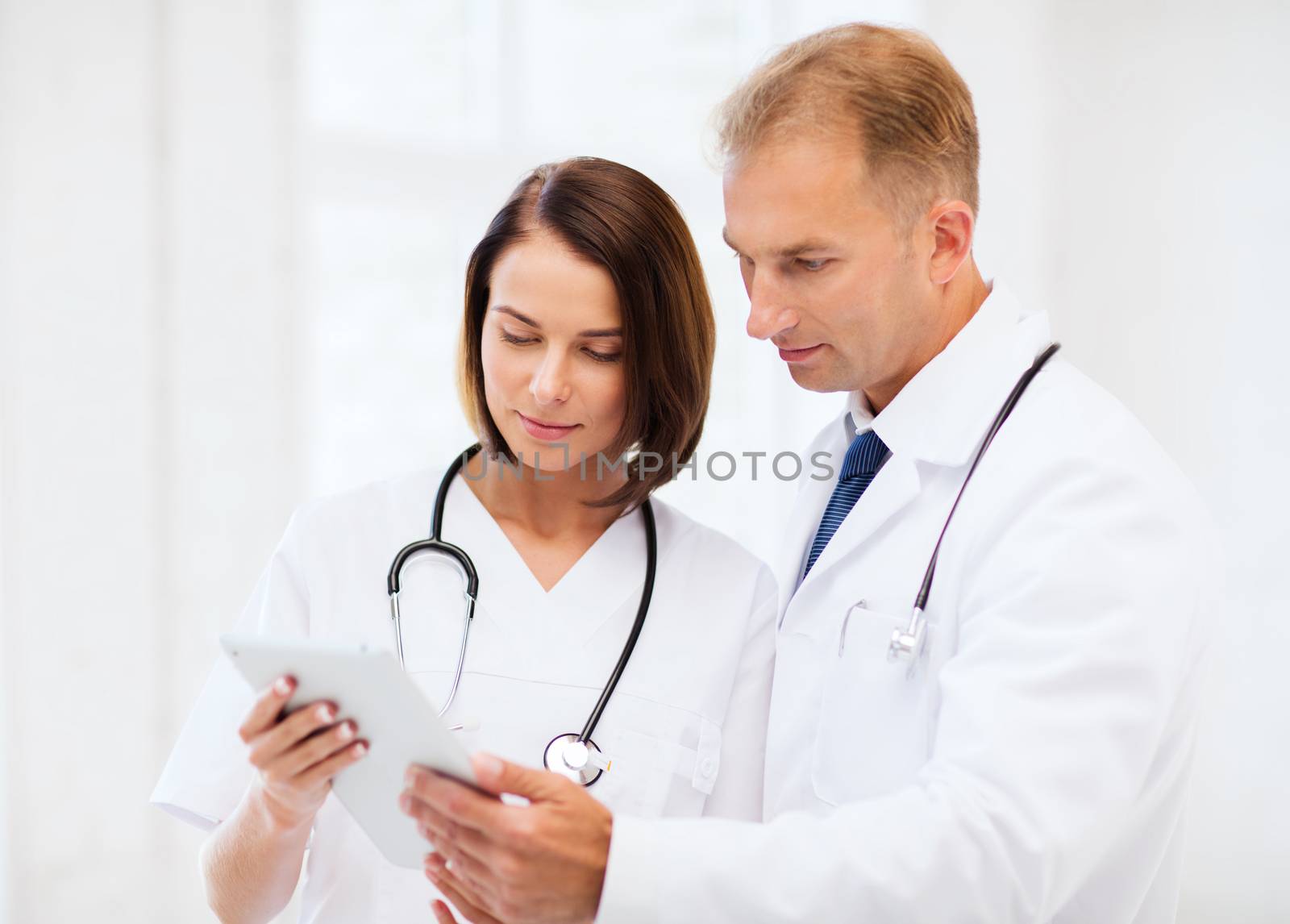 two doctors looking at tablet pc by dolgachov