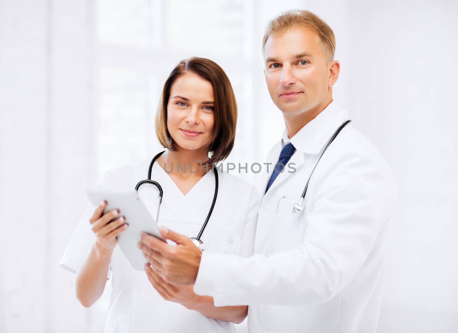 two doctors looking at tablet pc by dolgachov