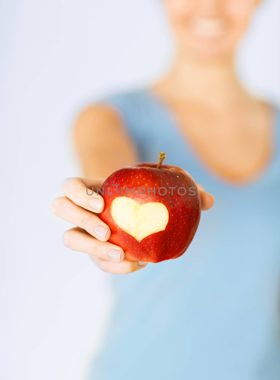 healthy food and lifestyle - woman hand holding red apple with heart shape