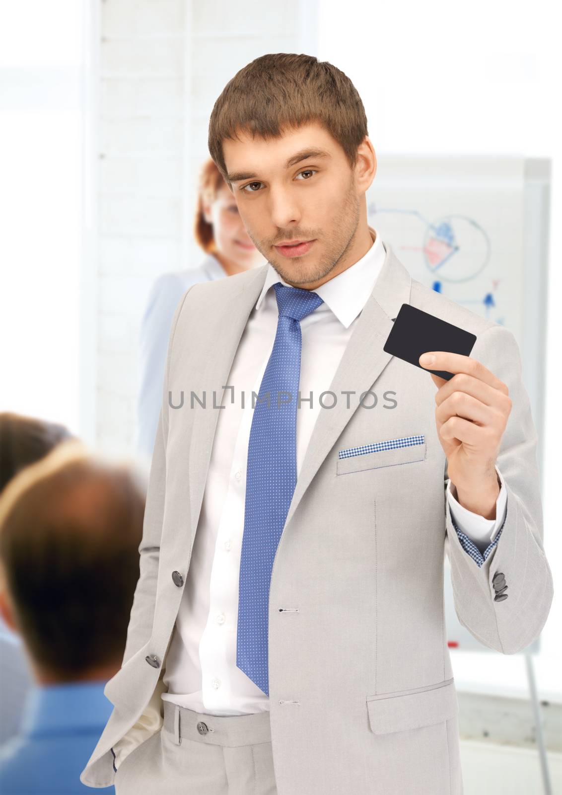 businessman showing credit card in office by dolgachov