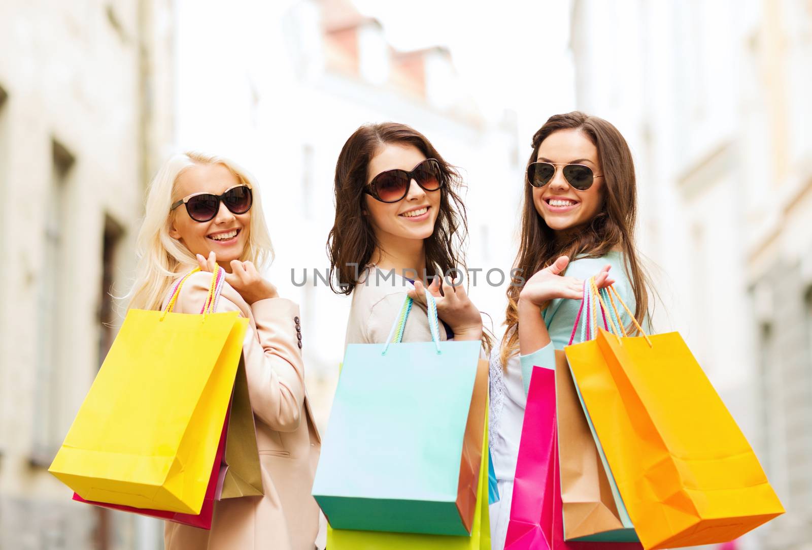 shopping and tourism concept - beautiful girls with shopping bags in ctiy