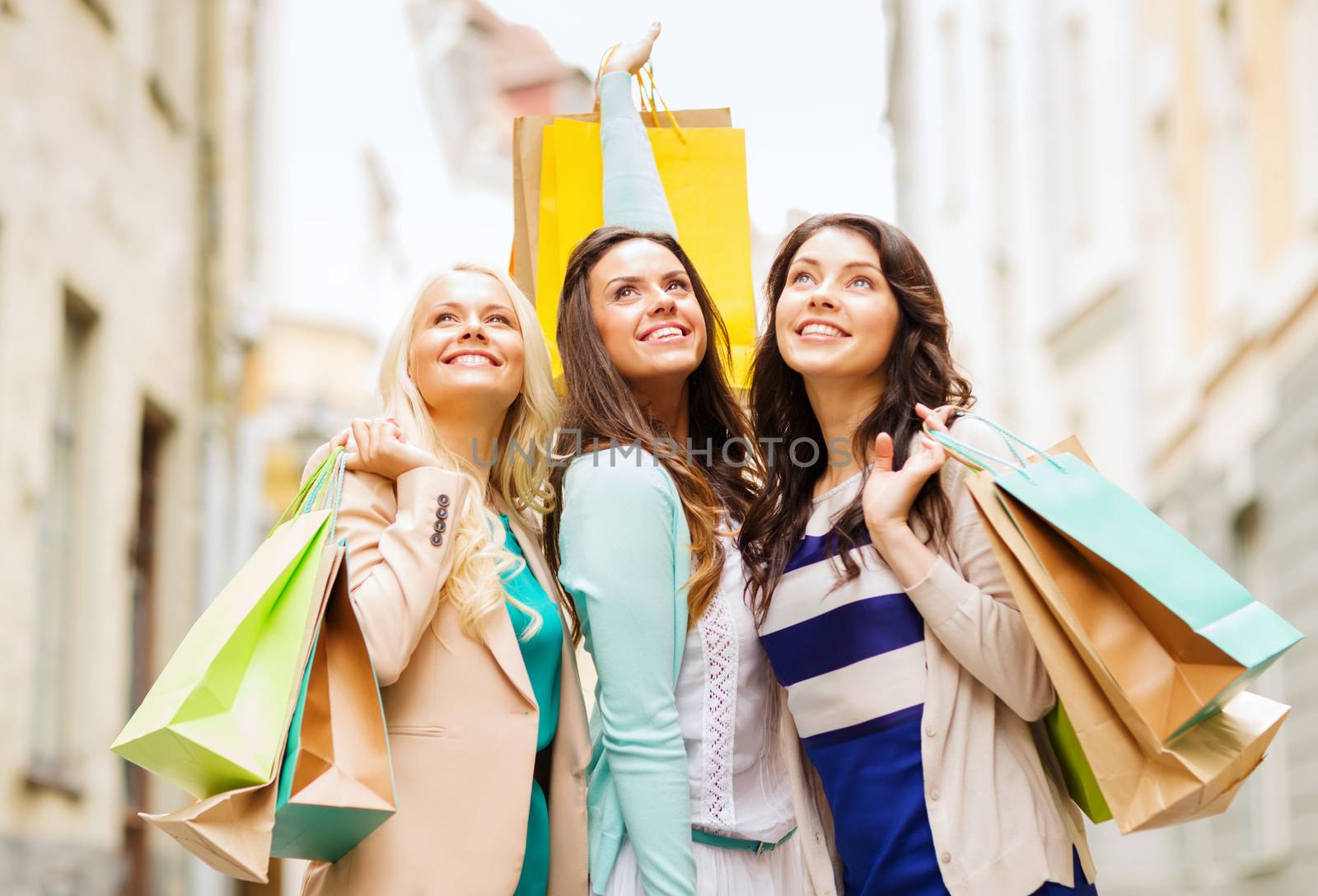 shopping and tourism concept - beautiful girls with shopping bags in ctiy