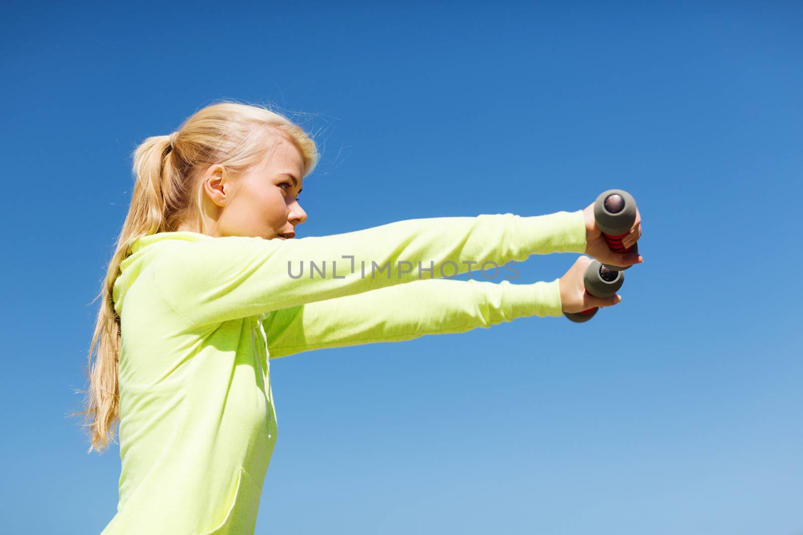 sporty woman with light dumbbells outdoors by dolgachov