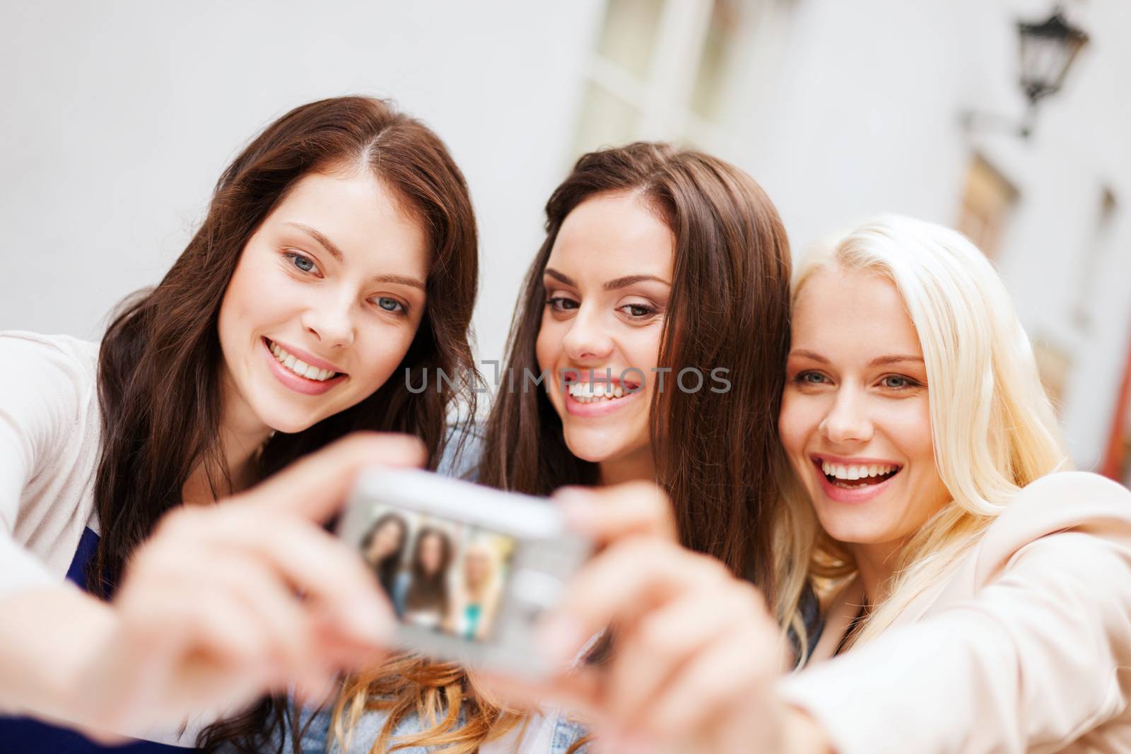 holidays and tourism concept - beautiful girls taking picture in the city