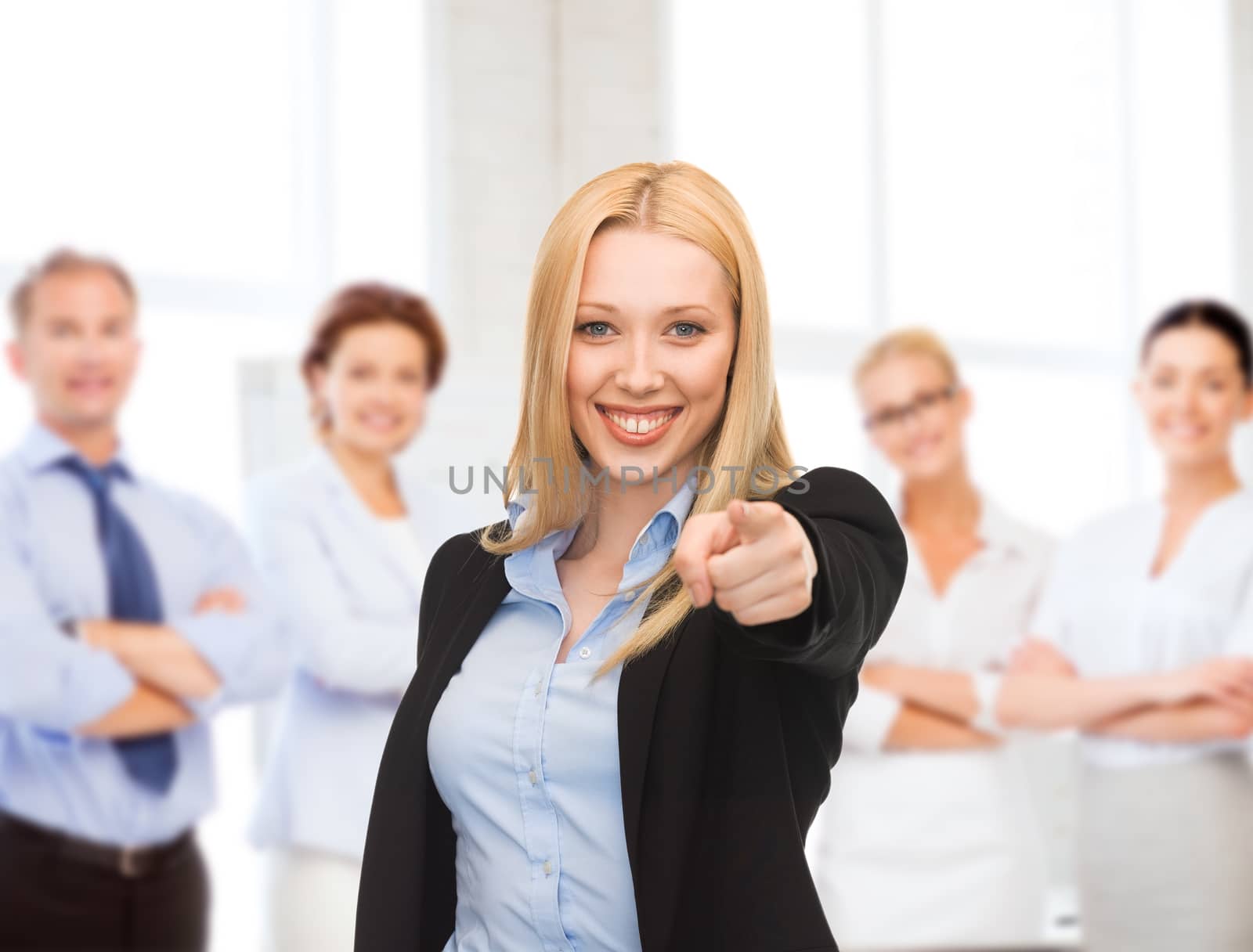 business concept - attractive young businesswoman pointing at you in office