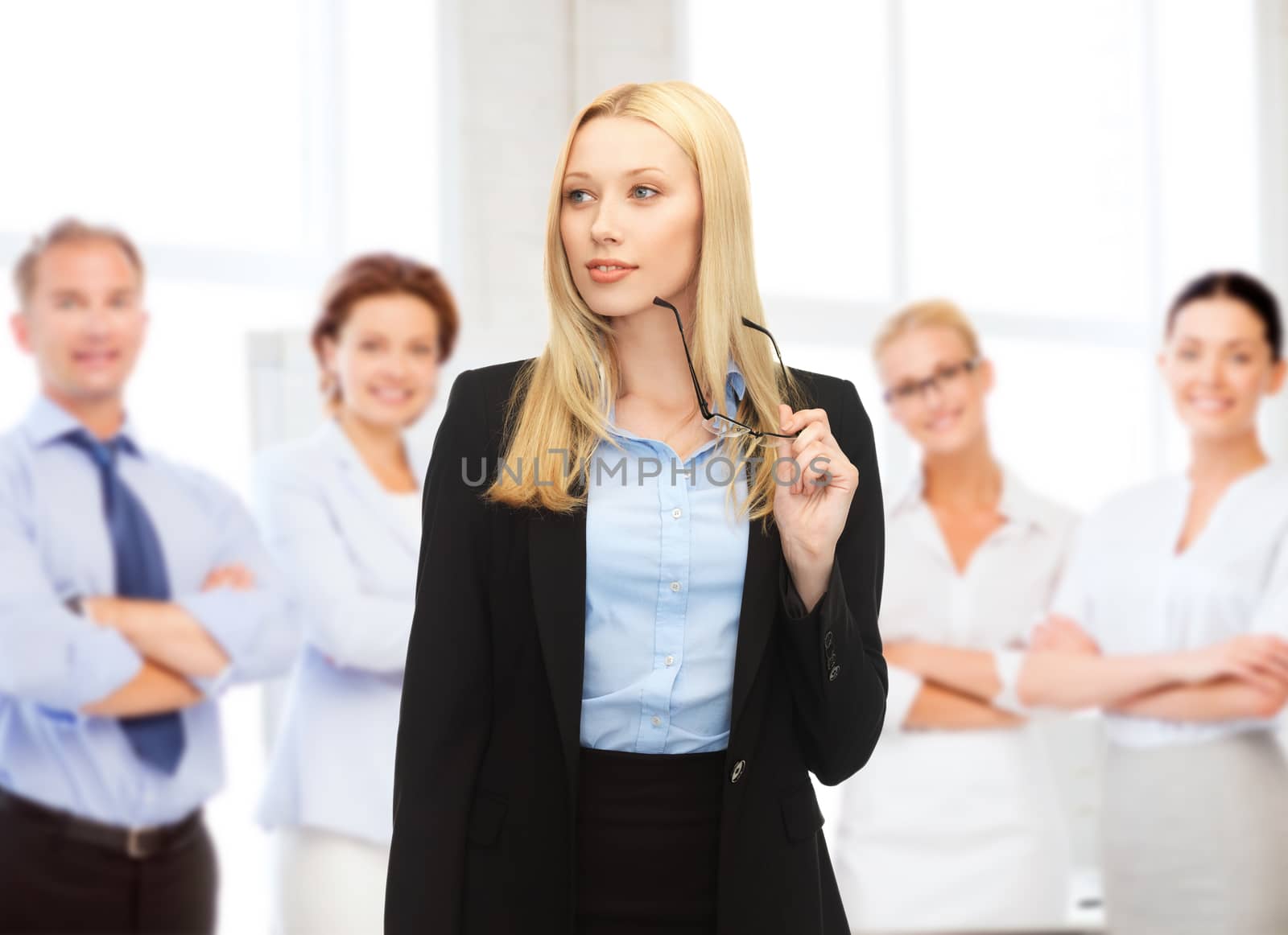 business concept - smiling businesswoman with eyeglasses and team behind