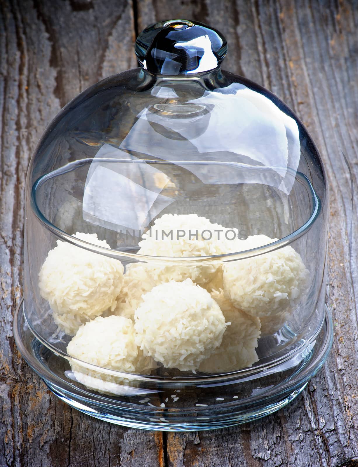 Glass Jar with Delicious Coconut Candies closeup on Rustic Wooden background