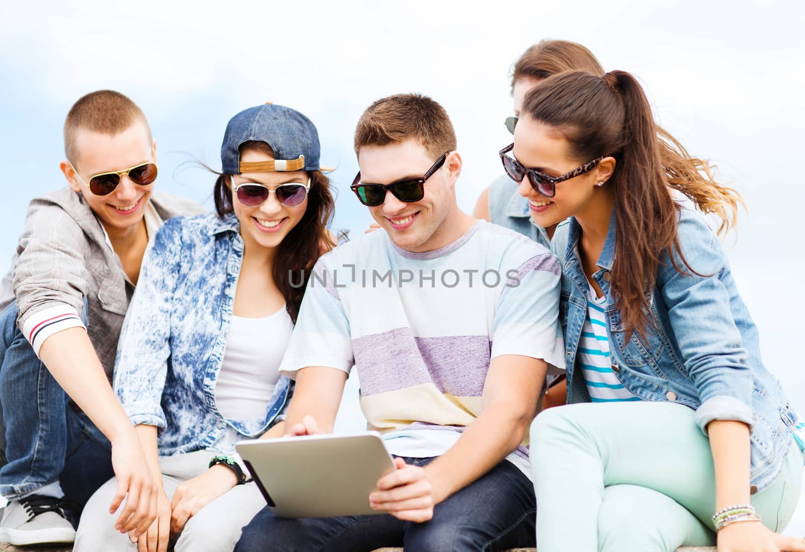 summer holidays, teenage and technology concept - group of teenagers looking at tablet pc