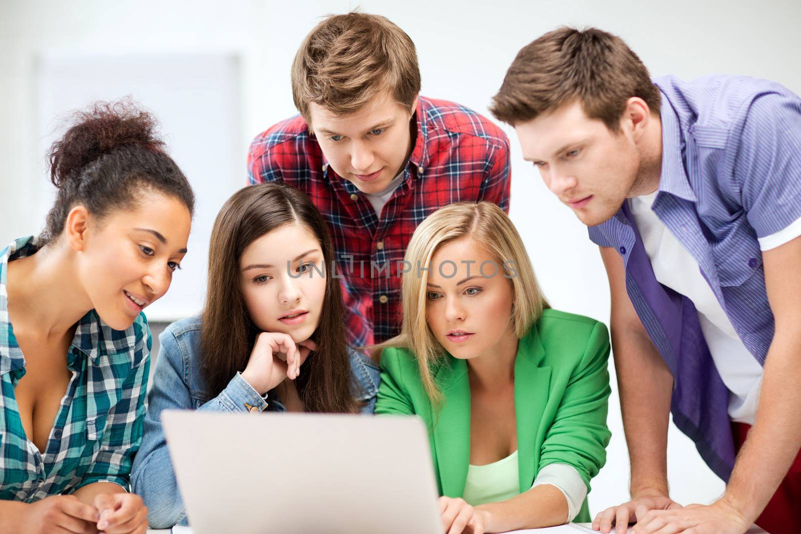 international students looking at laptop at school by dolgachov