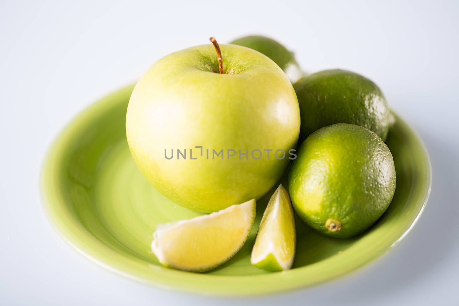 healthy food and cooking concept - green apple with limes in green bowl