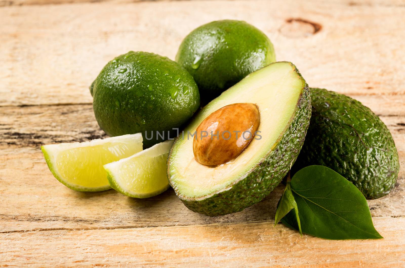 avocado and limes on wooden background by dolgachov