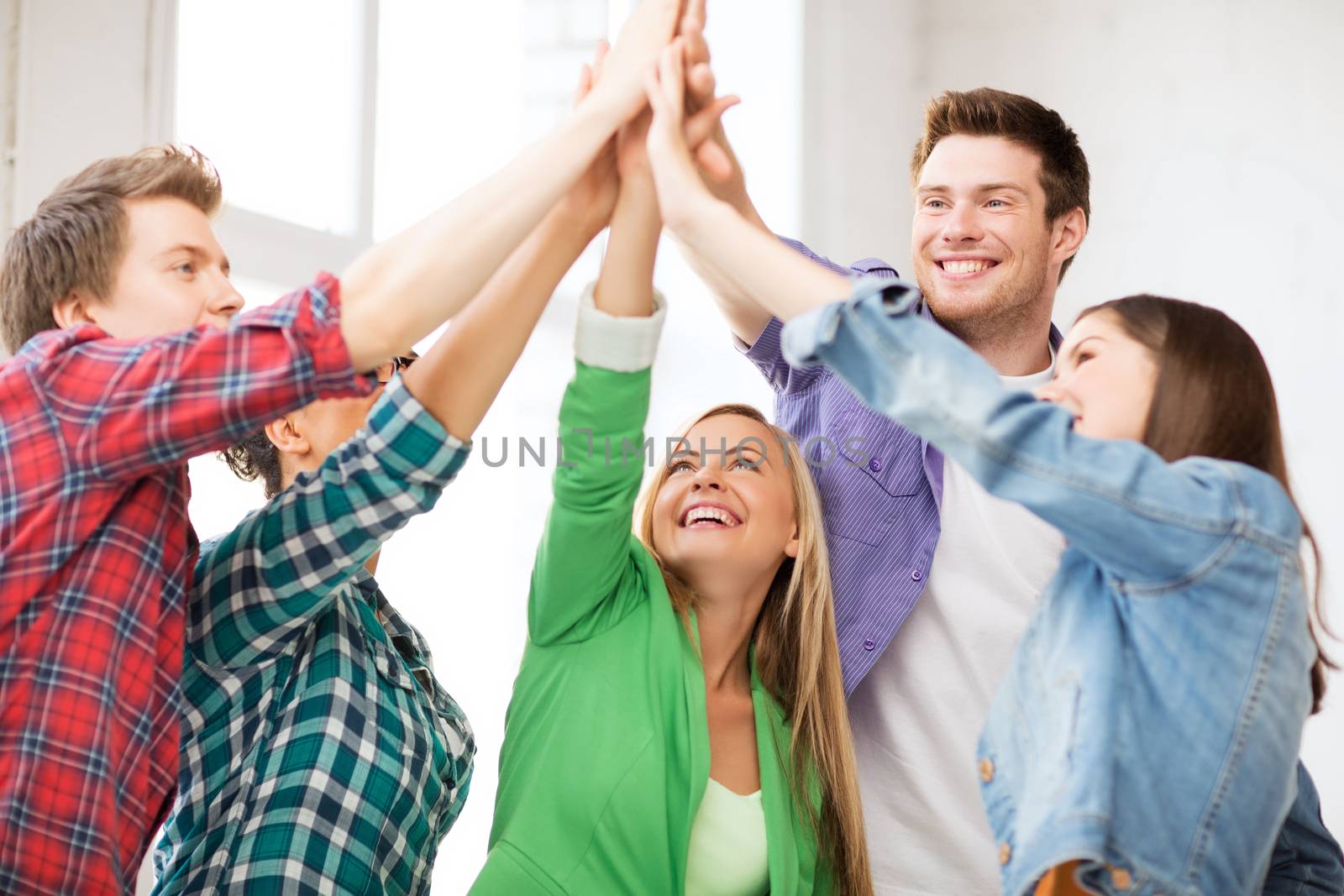 happy students giving high five at school by dolgachov