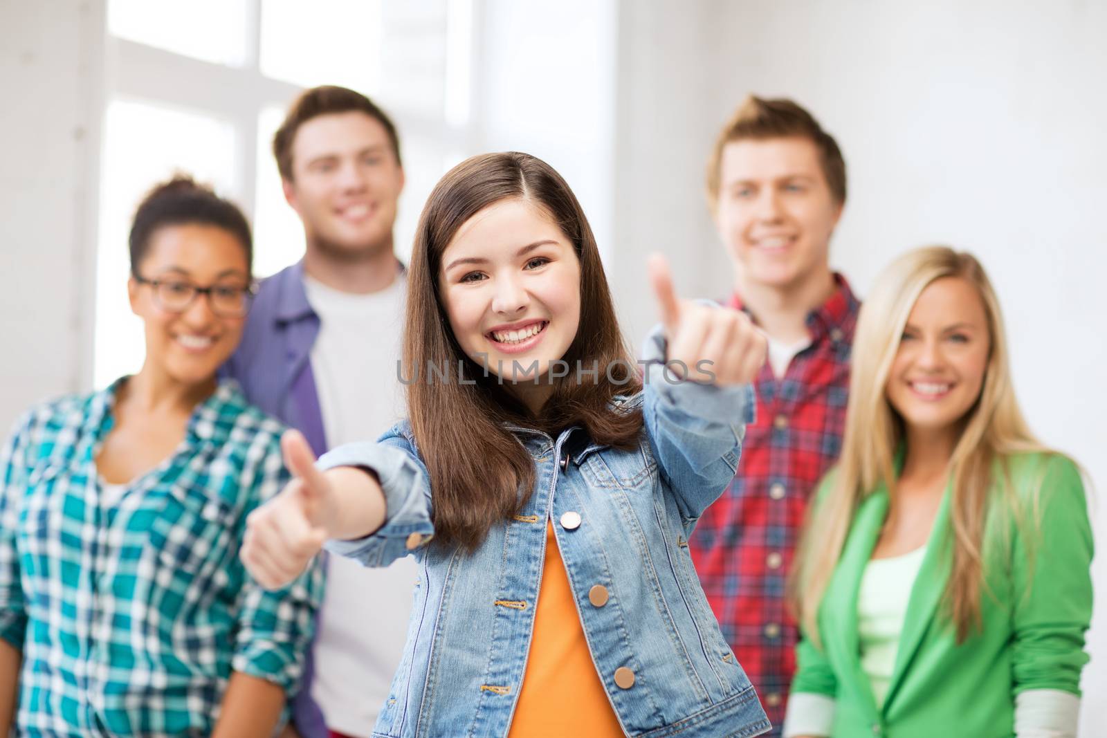 education concept - happy team of students showing thumbs up at school