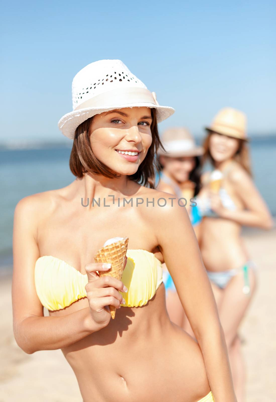 summer holidays and vacation - girl in bikini eating ice cream on the beach