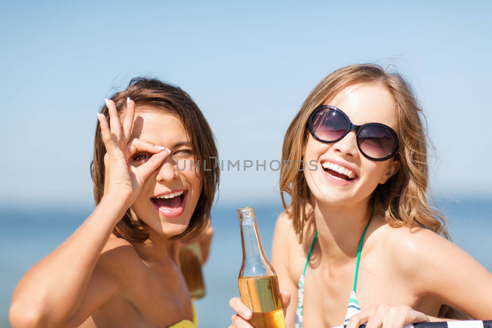 summer holidays and vacation - girls in bikinis with drinks on the beach chairs