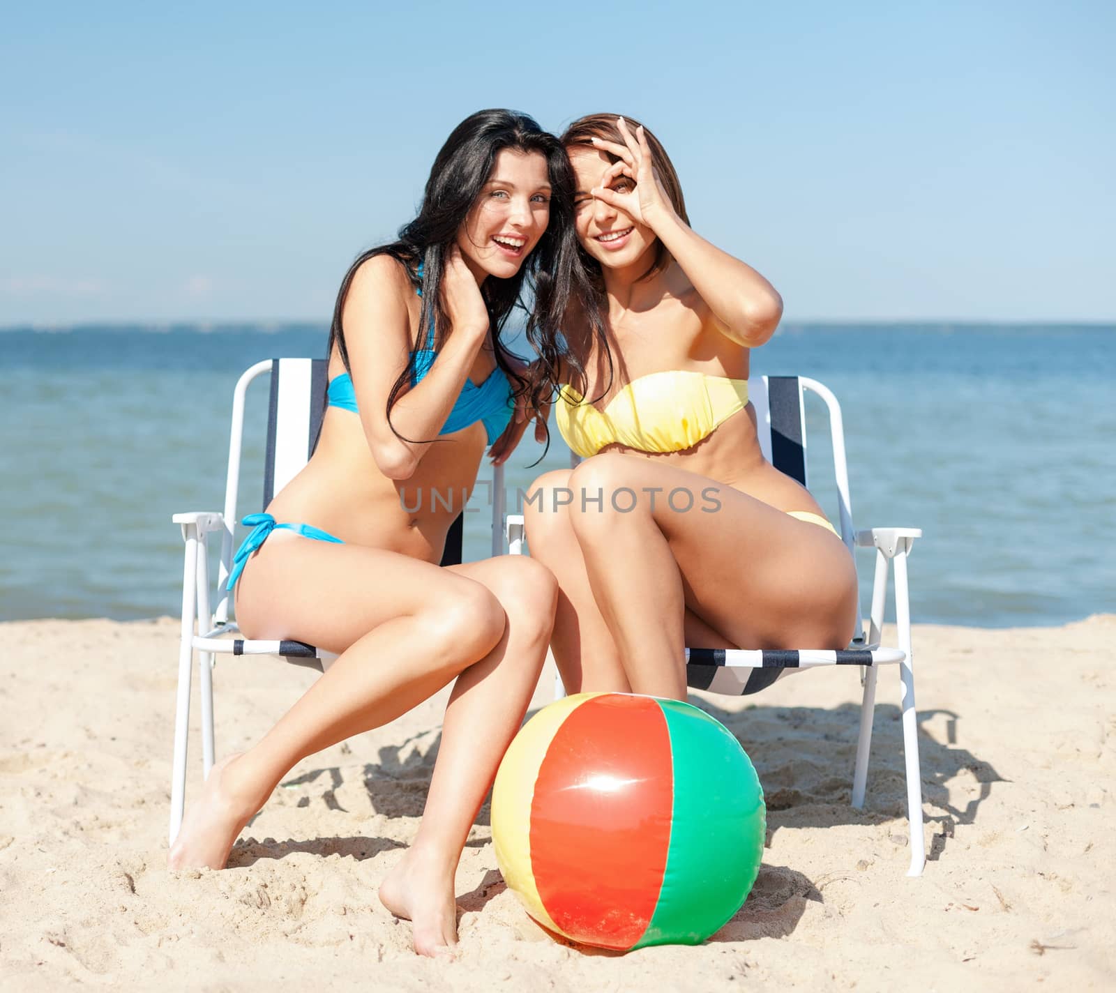 summer holidays and vacation - girls in bikinis sunbathing on the beach chairs