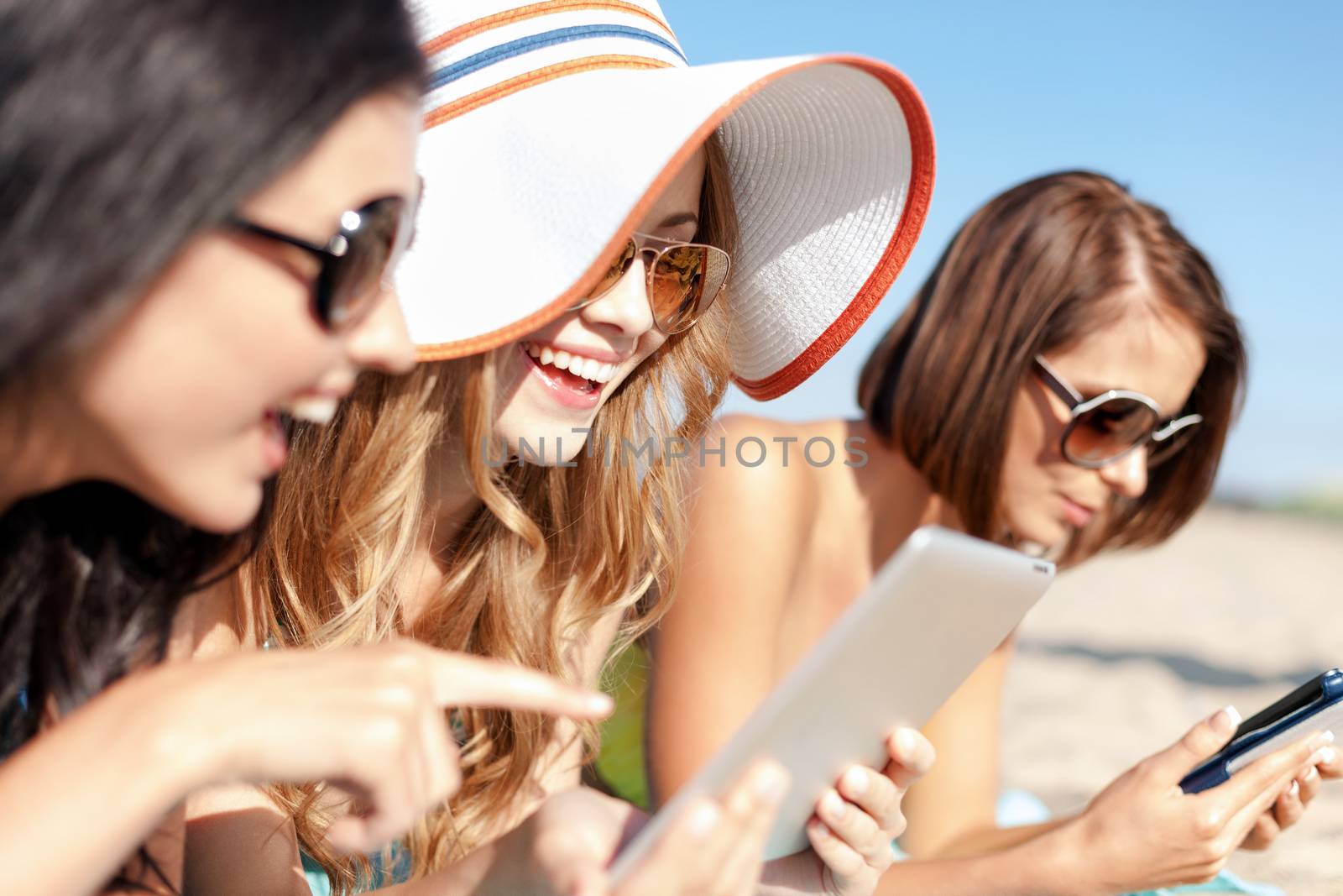 girls with tablet pc on the beach by dolgachov