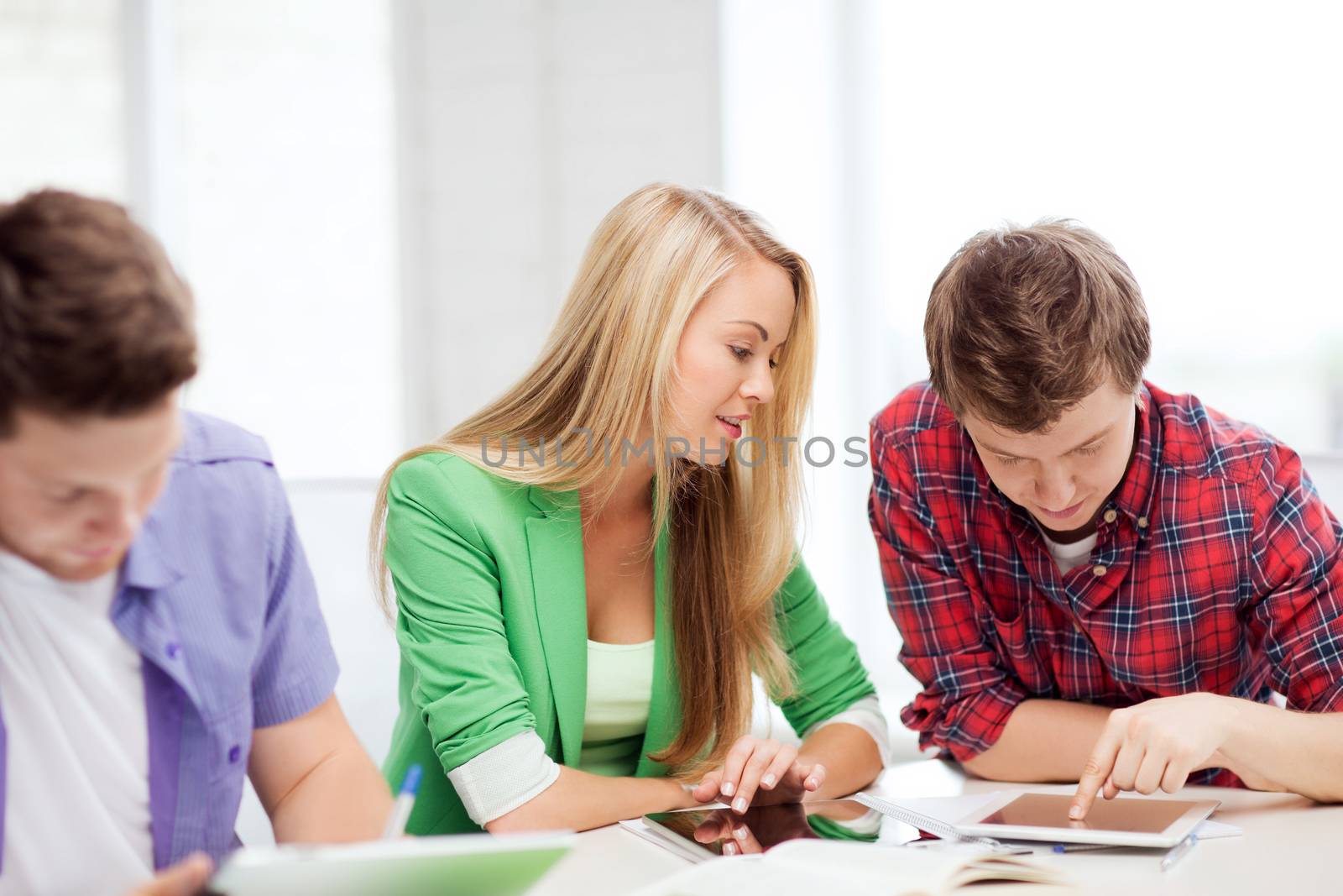 students browsing in tablet pc at school by dolgachov