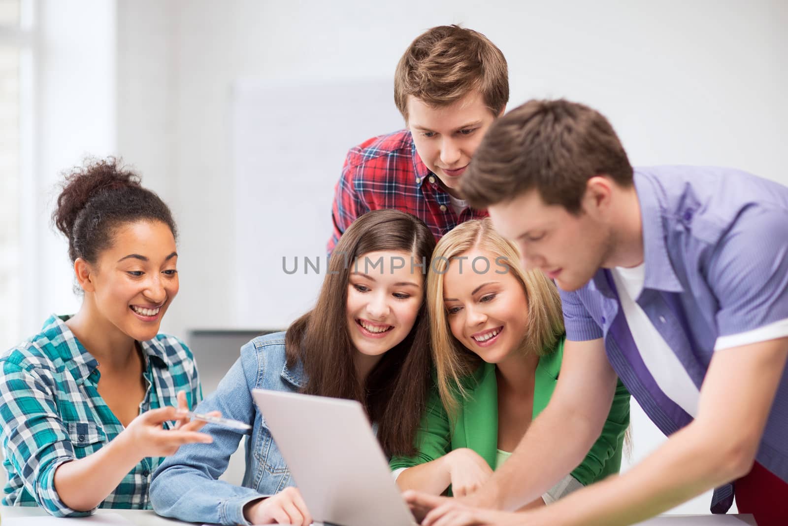 international students looking at laptop at school by dolgachov