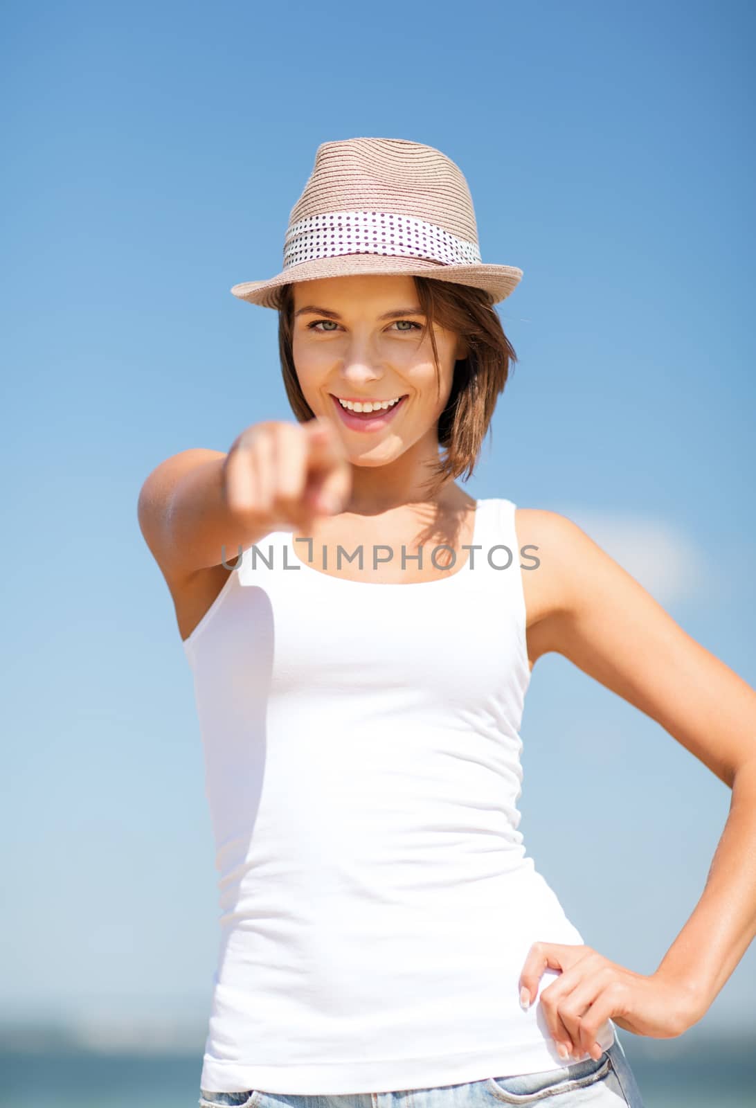 summer holidays and vacation - girl in hat pointing at you on the beach