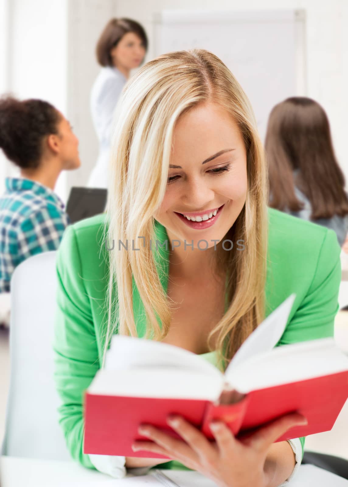 education concept - smiling student girl reading book at school