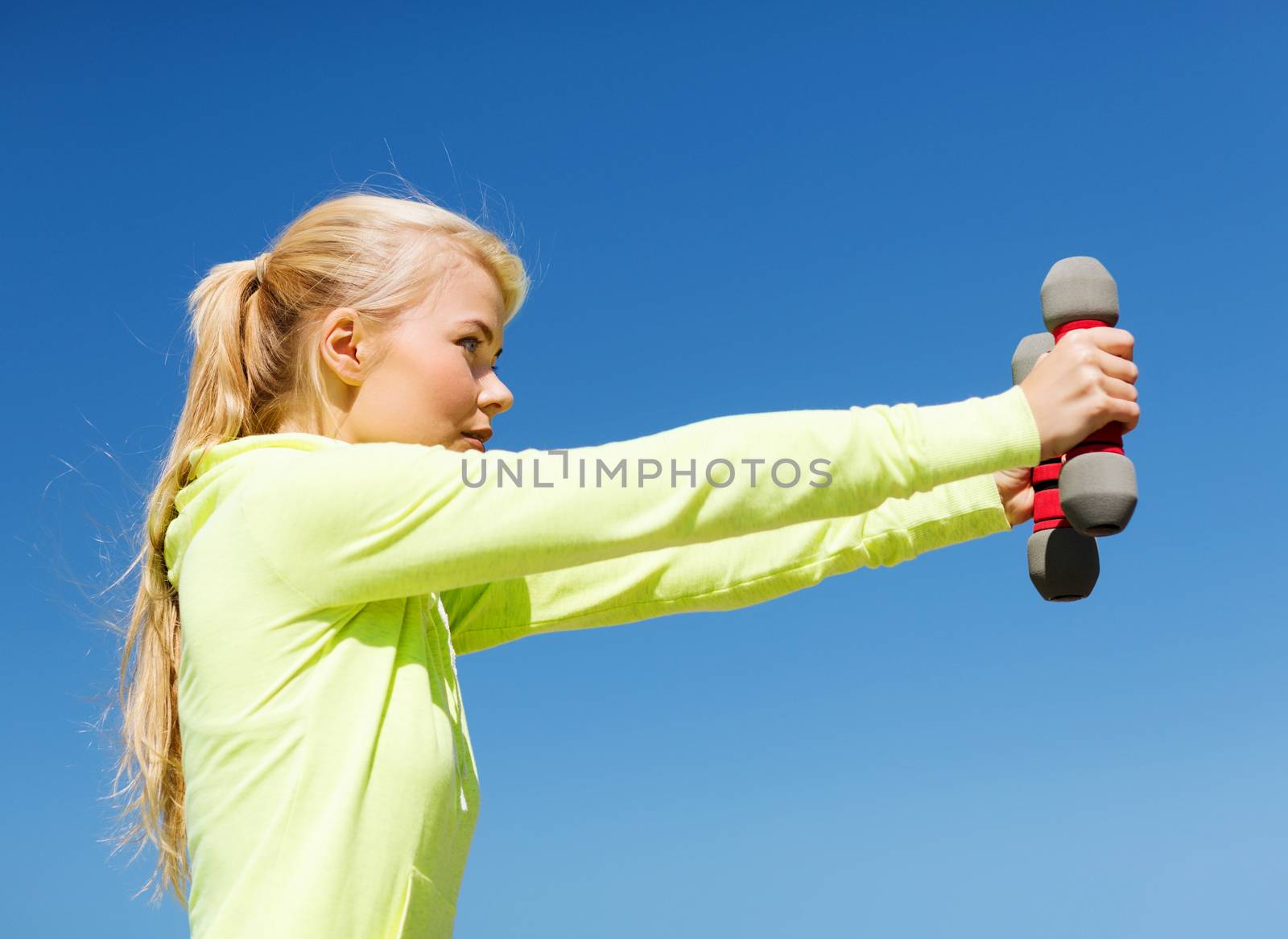 sport and lifestyle - young sporty woman with light dumbbells outdoors