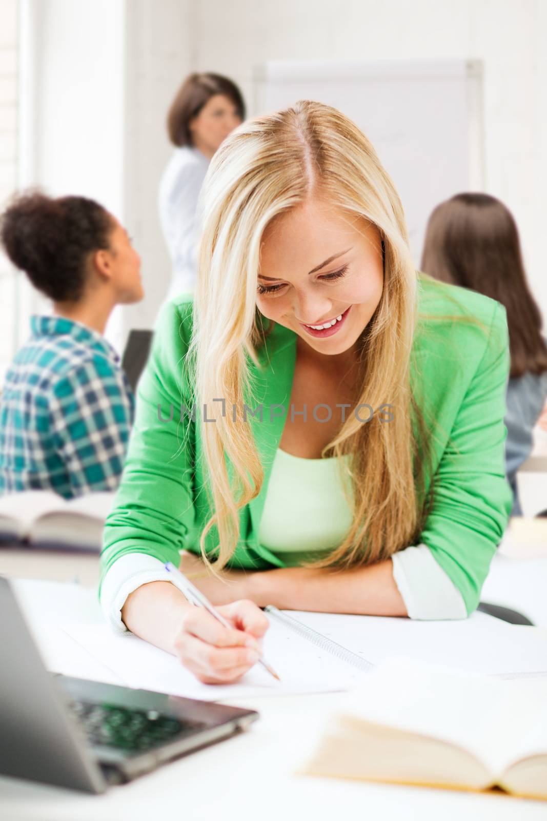 student girl writing in notebook at school by dolgachov
