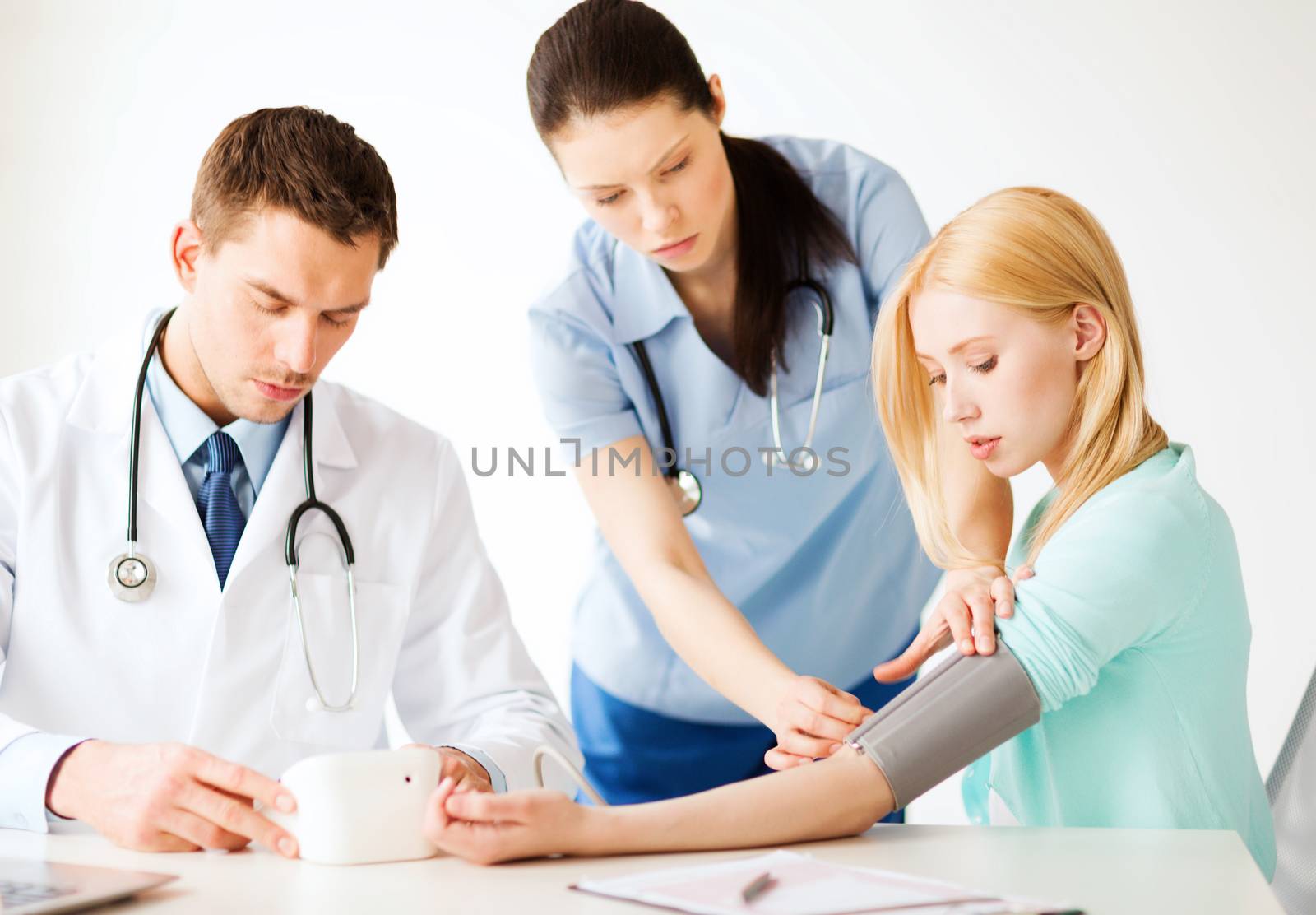 healthcare and medical concept - doctor and nurse with patient measuring blood pressure in hospital