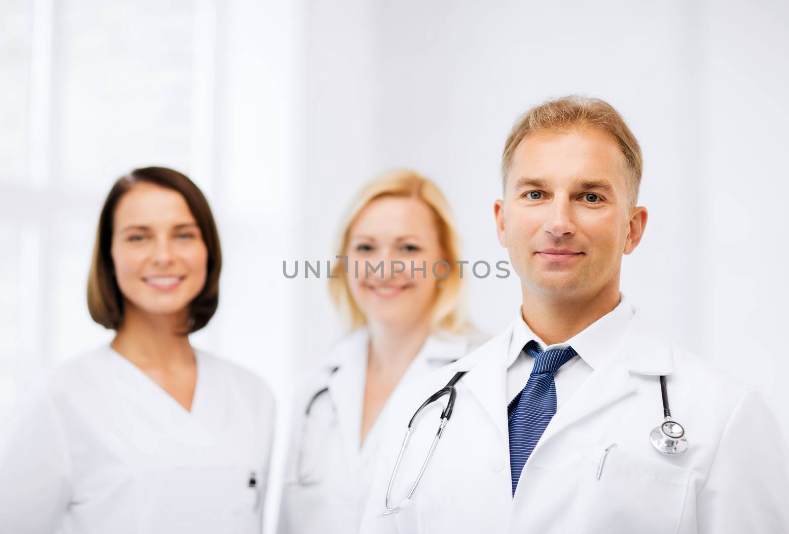 healthcare and medical concept - male doctor with stethoscope and colleagues