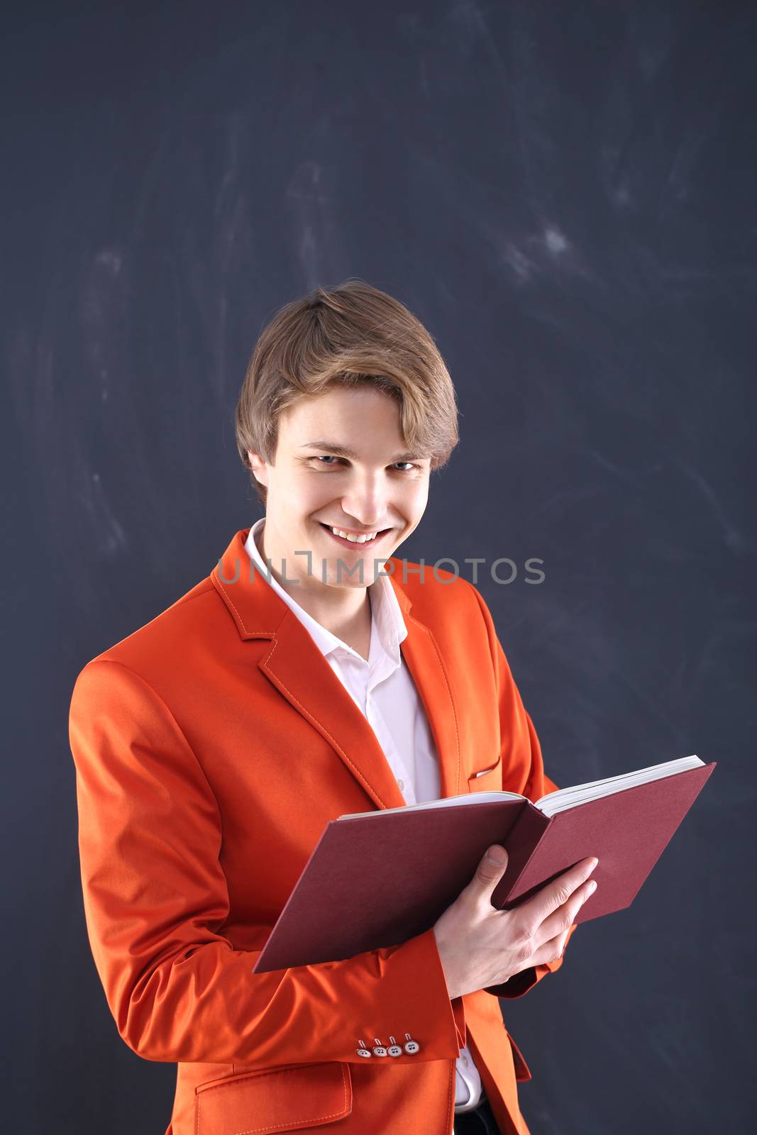 Portrait of a young, handsome man standing against the background of blackboard