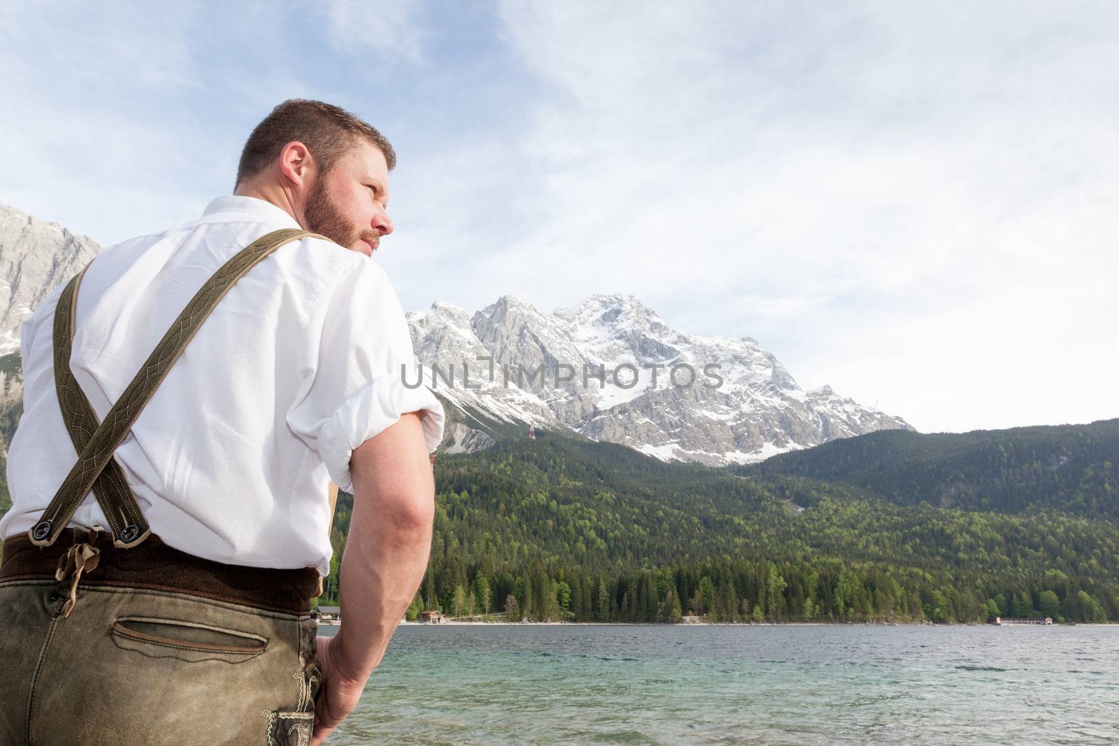 A traditional bavarian man at lake Eibsee with the Zugspitze mountain in the background