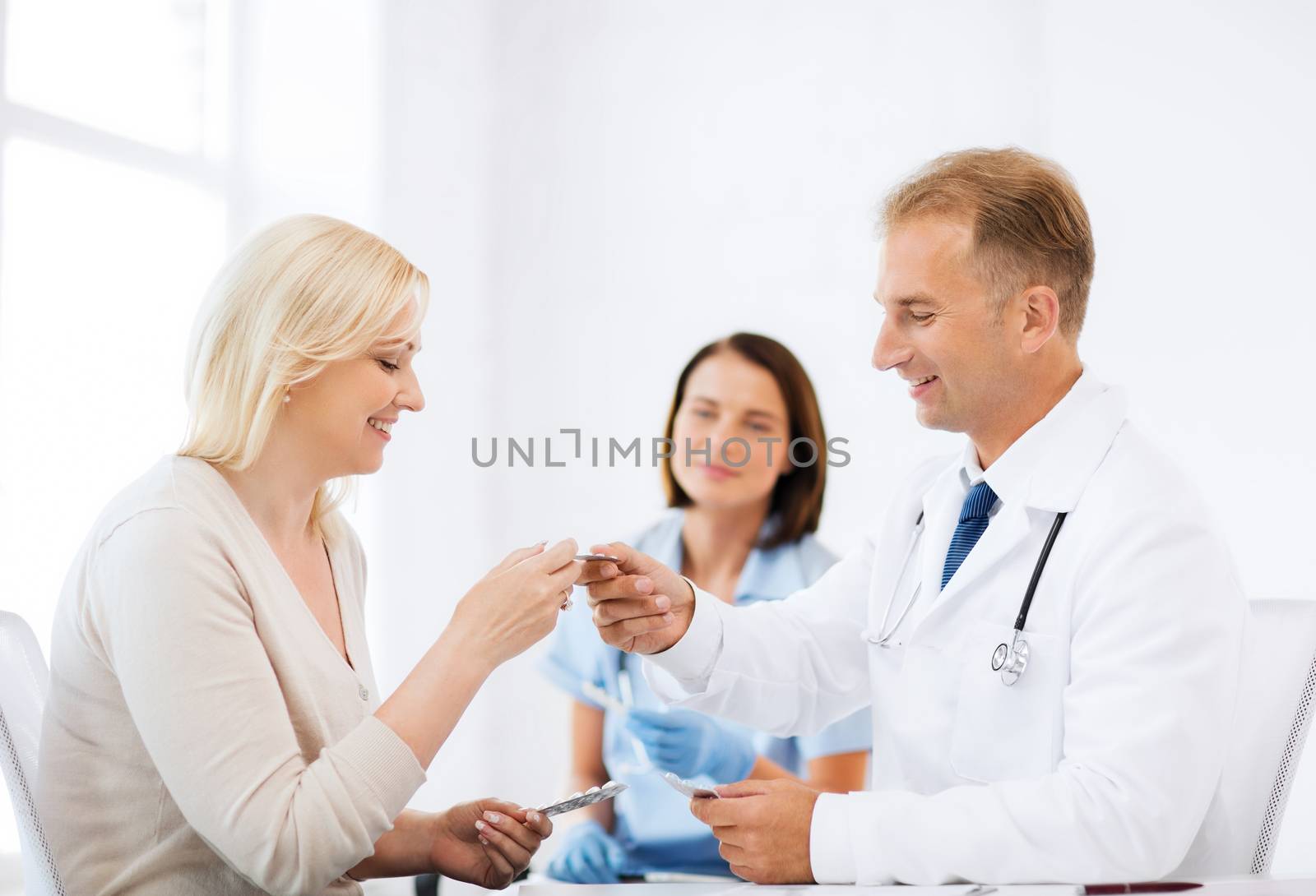 healthcare and medical concept - doctor giving tablets to patient in hospital