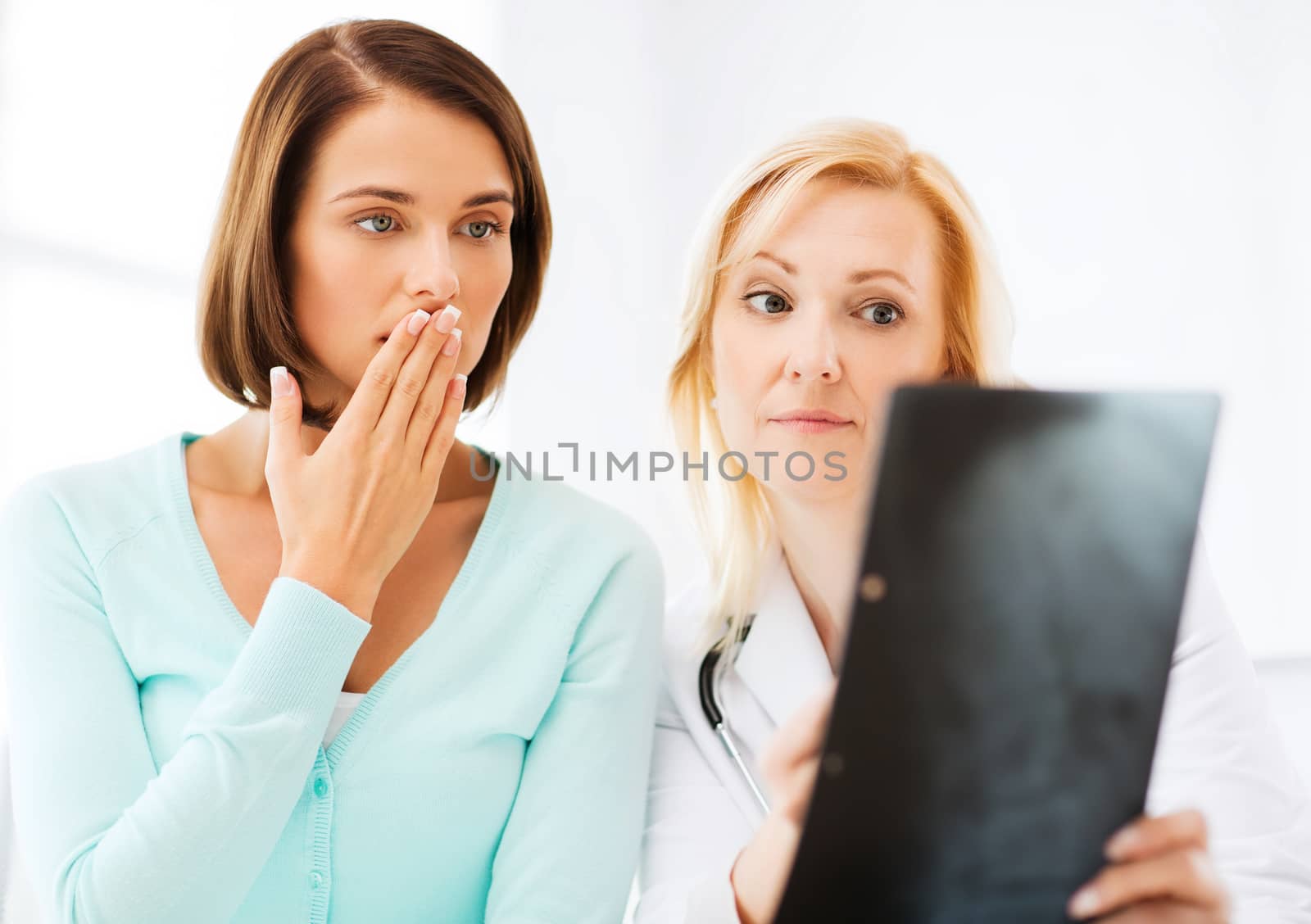 doctor with patients looking at x-ray by dolgachov