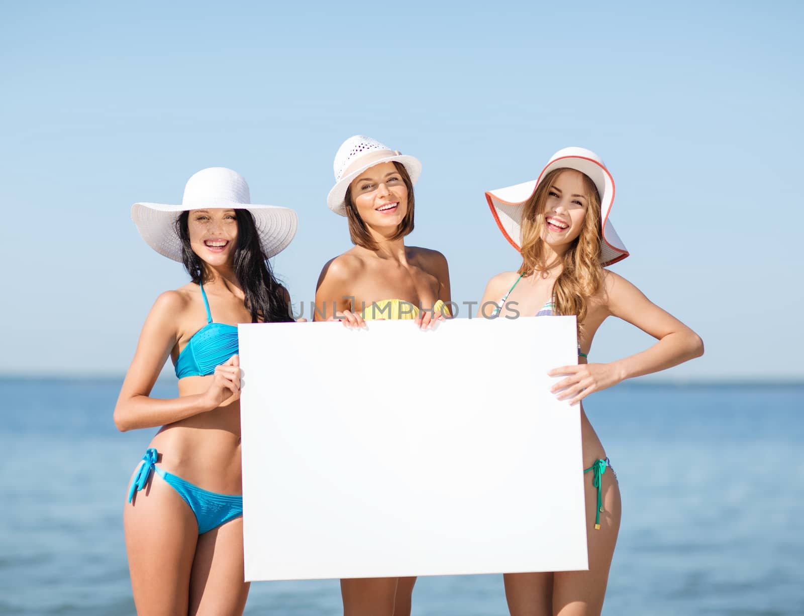 summer holidays and vacation - girls in bikinis holding blank white board on the beach