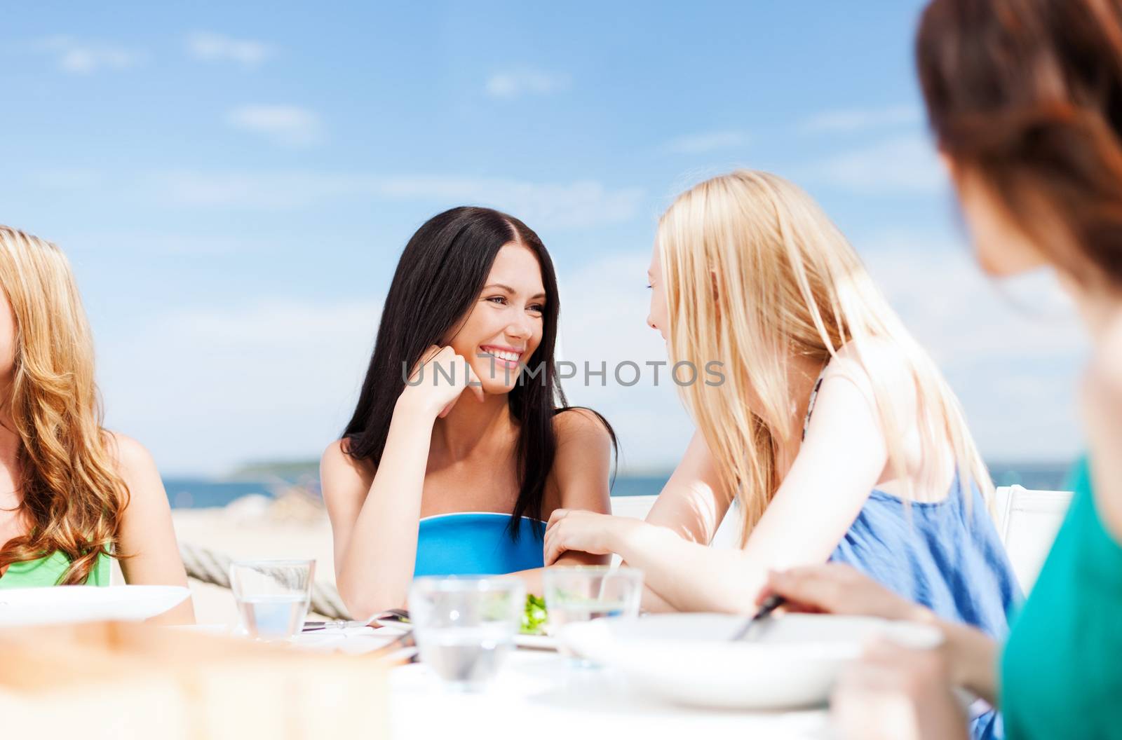 summer holidays and vacation - girls in cafe on the beach