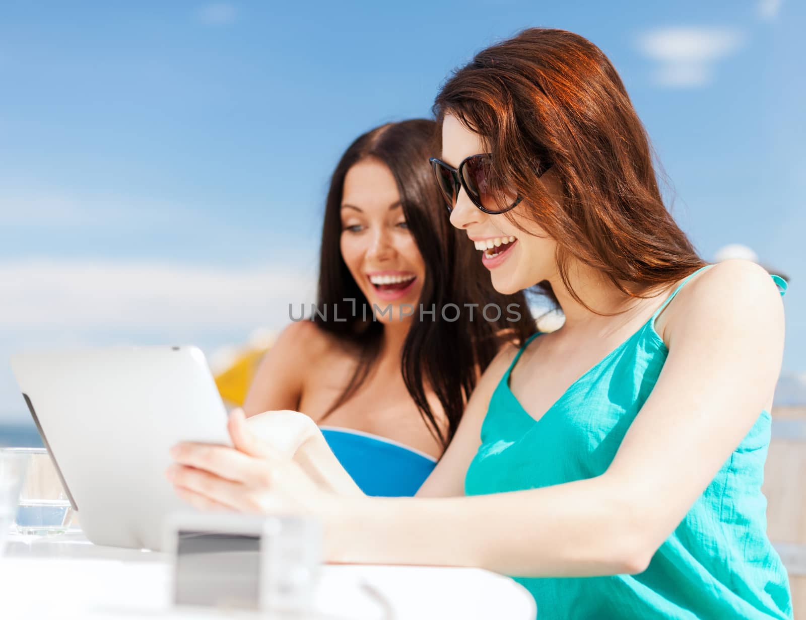 girls looking at tablet pc in cafe by dolgachov