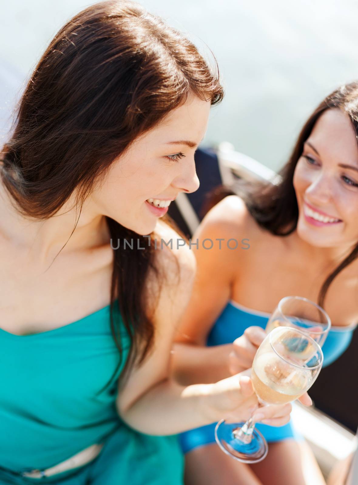 summer holidays and vacation - girls with champagne glasses on boat or yacht