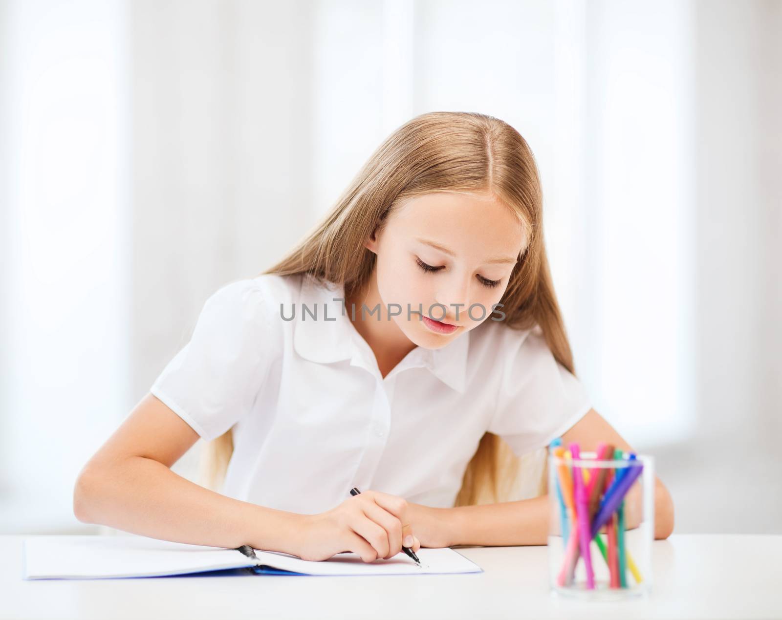 education and school concept - little student girl drawing at school