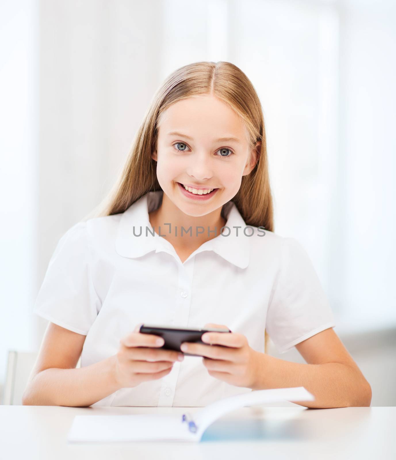 education, school, technology and internet concept - little student girl with smartphone at school