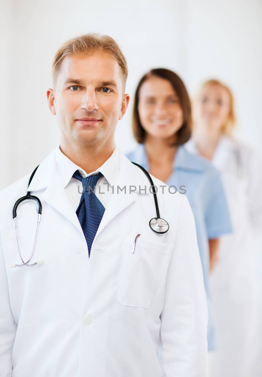 healthcare and medical concept - male doctor with stethoscope and colleagues