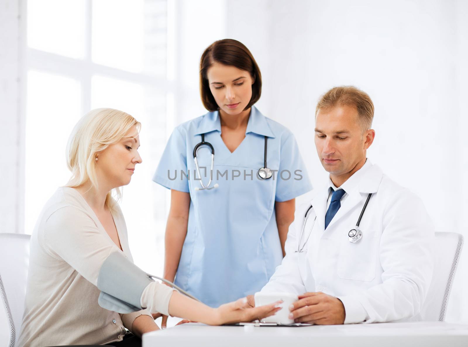 healthcare and medical concept - doctor and nurse with patient measuring blood pressure