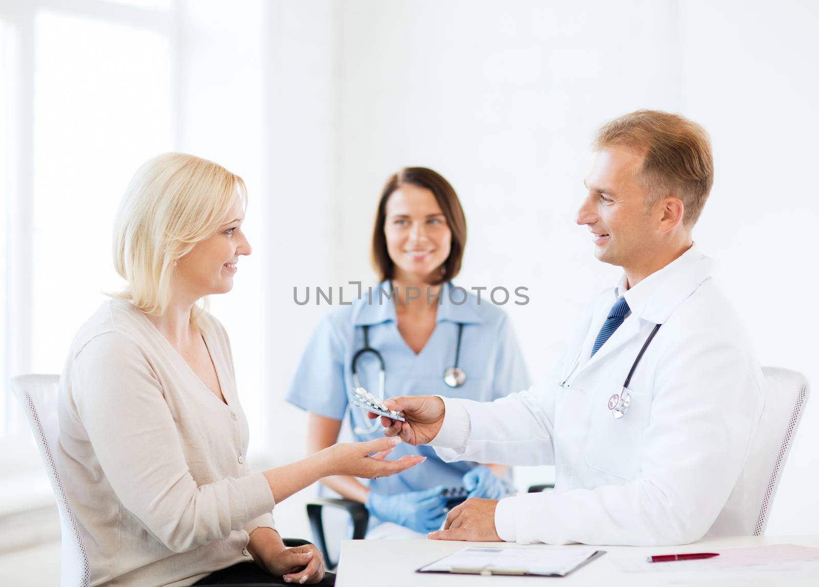 healthcare and medical concept - doctor giving tablets to patient in hospital