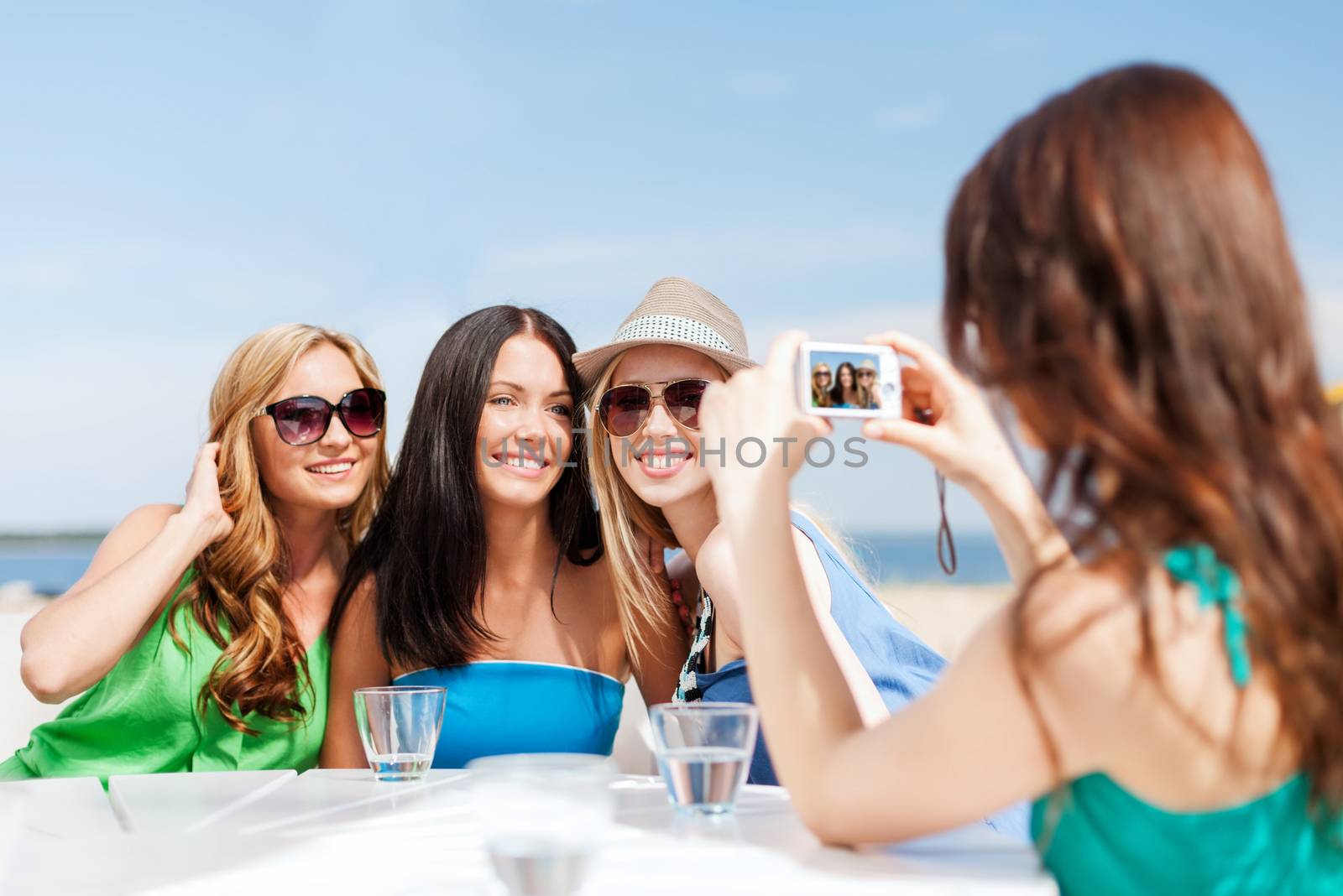 summer holidays and vacation - girls taking photo with digital camera in cafe on the beach