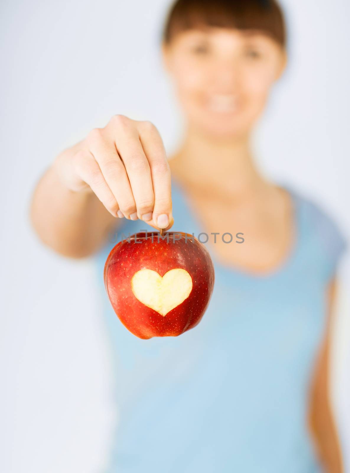 healthy food and lifestyle - woman hand holding red apple with heart shape