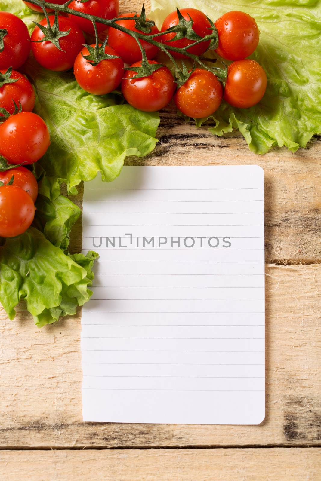 food and cooking concept - cherry tomatoes on wood background with white blank paper