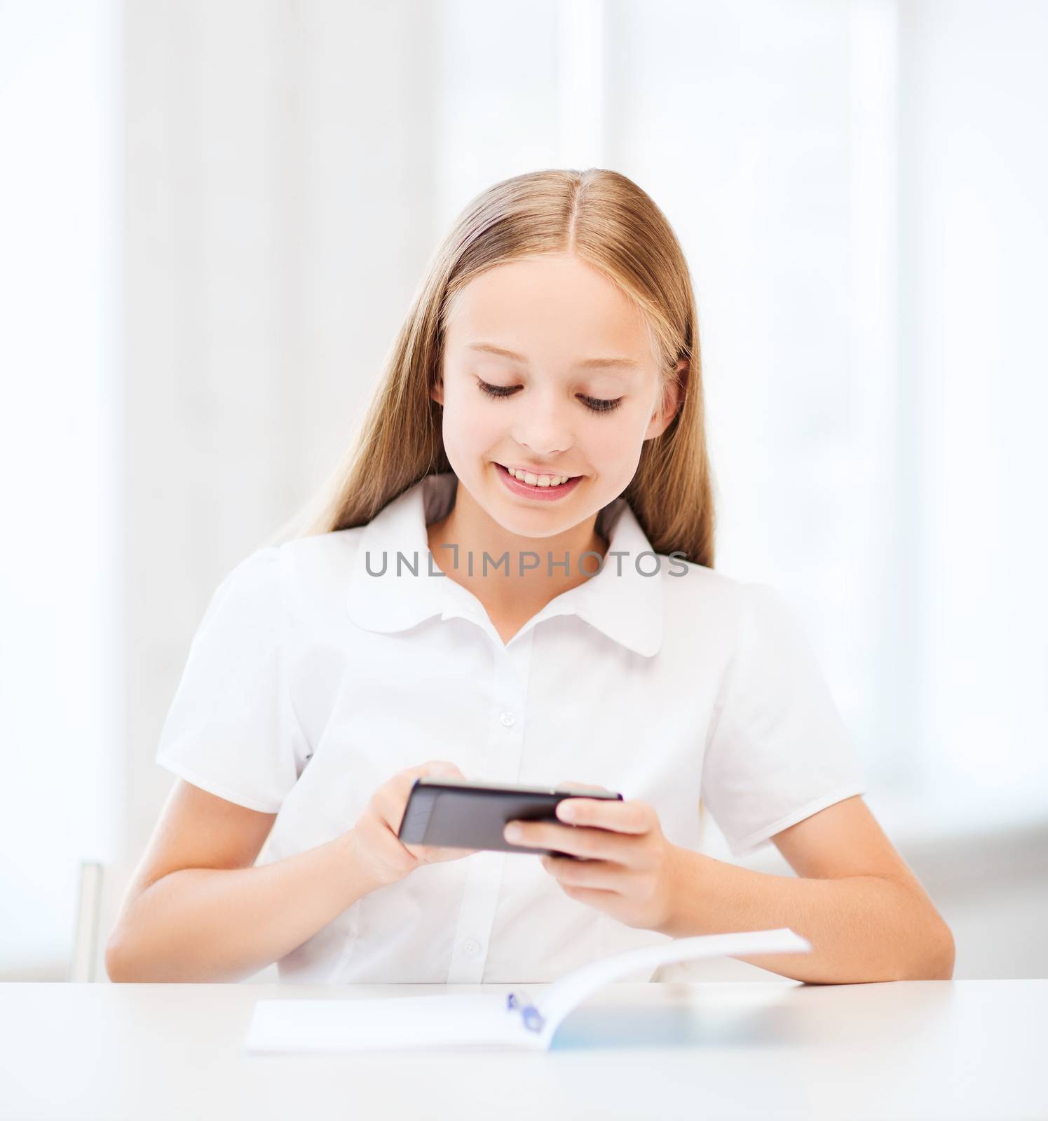 education, school, technology and internet concept - little student girl with smartphone at school