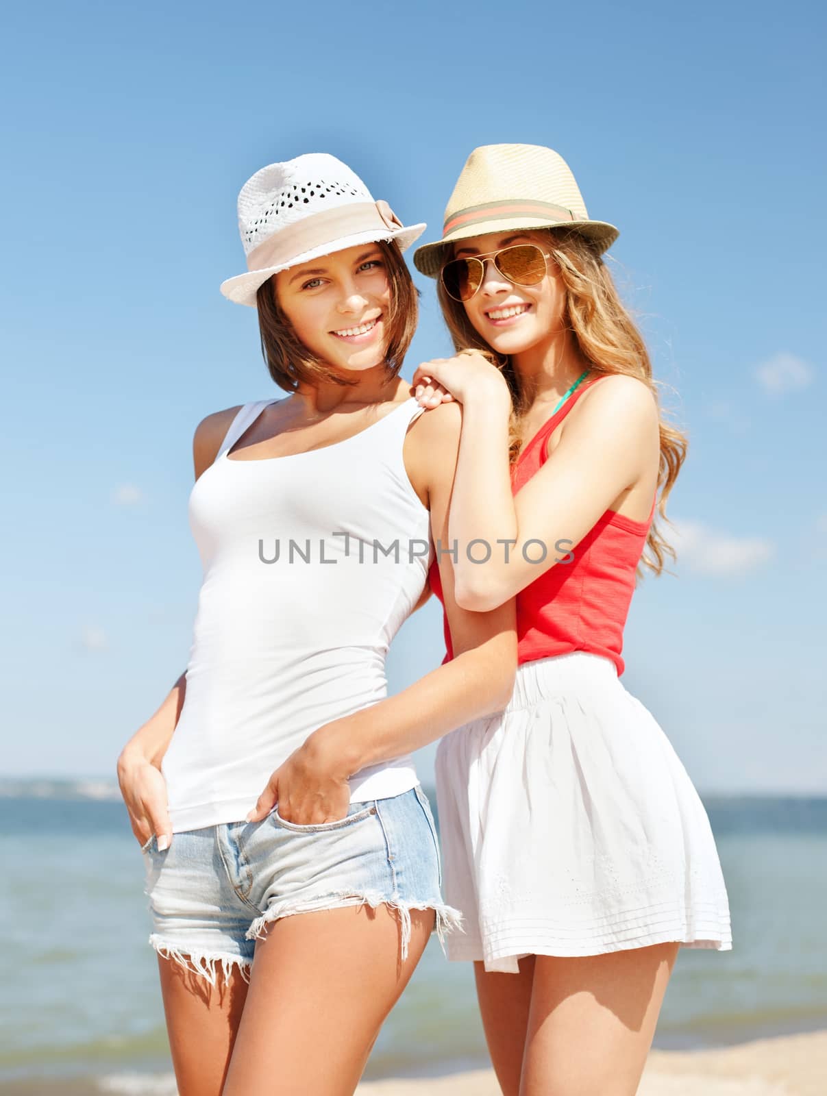 summer holidays and vacation concept - girls in hats on the beach