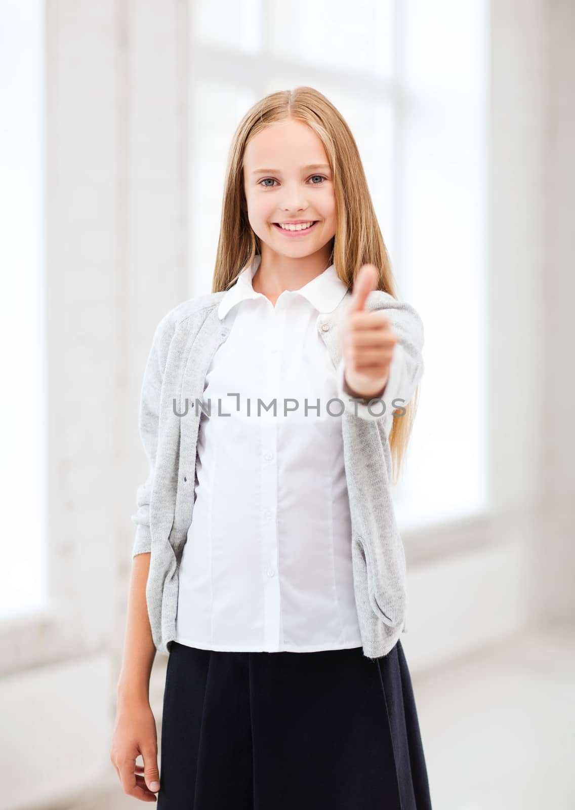education and school concept - little student girl showing thumbs up at school