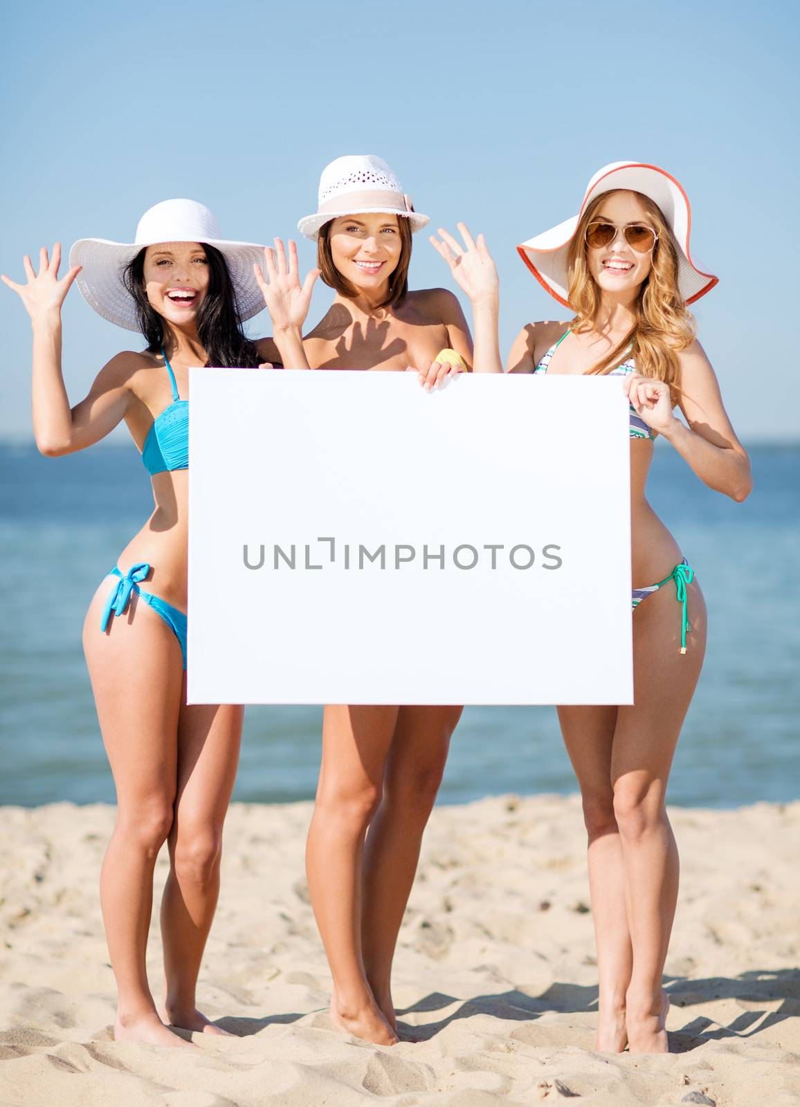 summer holidays and vacation - girls in bikinis holding blank white board on the beach