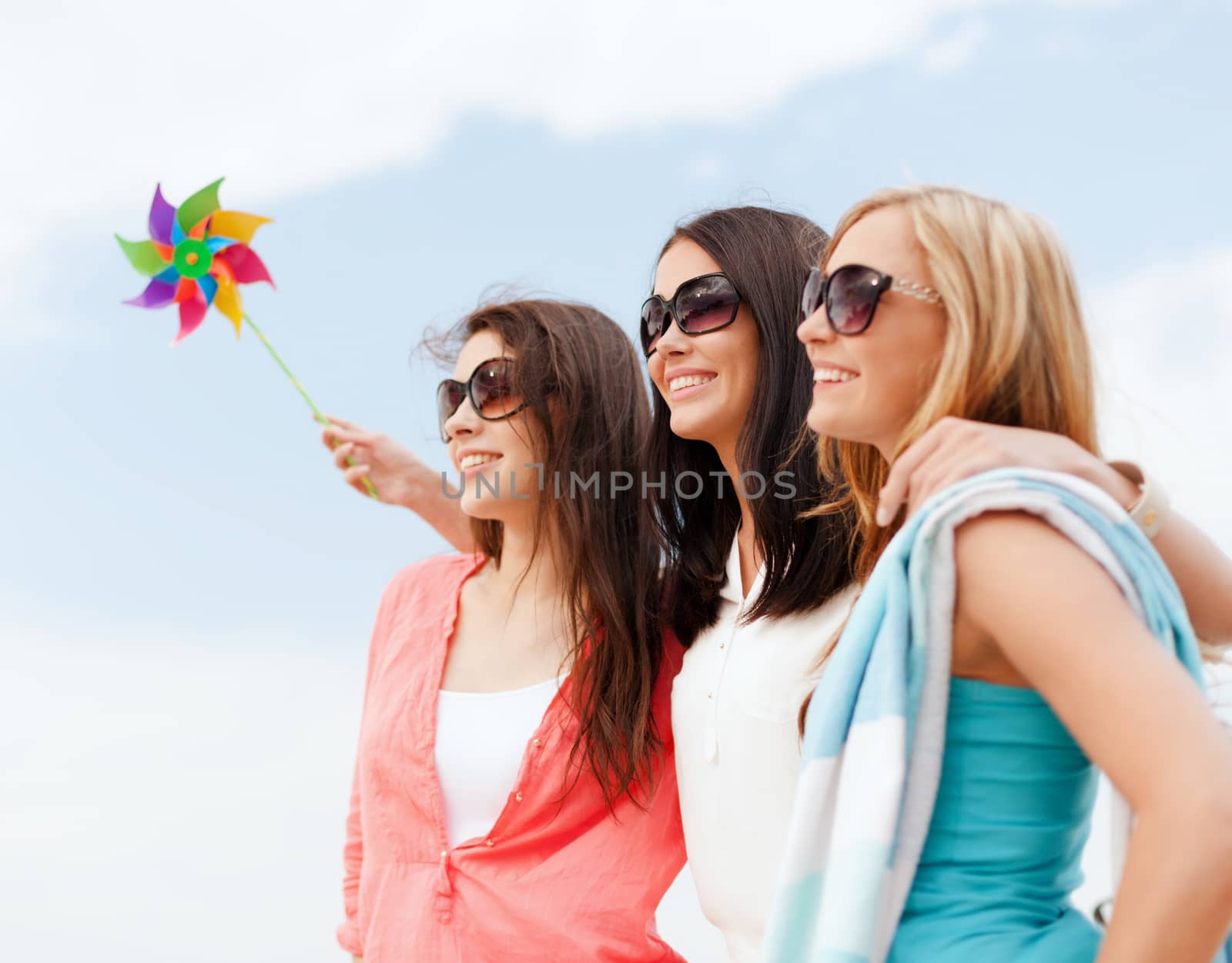 summer holidays, vacation and ecology concept - girls with windmill toy on the beach